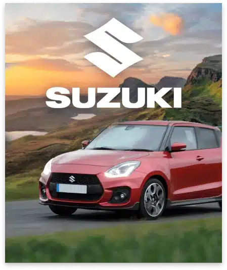 A red Suzuki car is driving on a scenic mountain road, captured beautifully by a video production agency. The logo and name "SUZUKI" are prominently displayed at the top of the image against a backdrop of a sunset sky and hilly landscape.