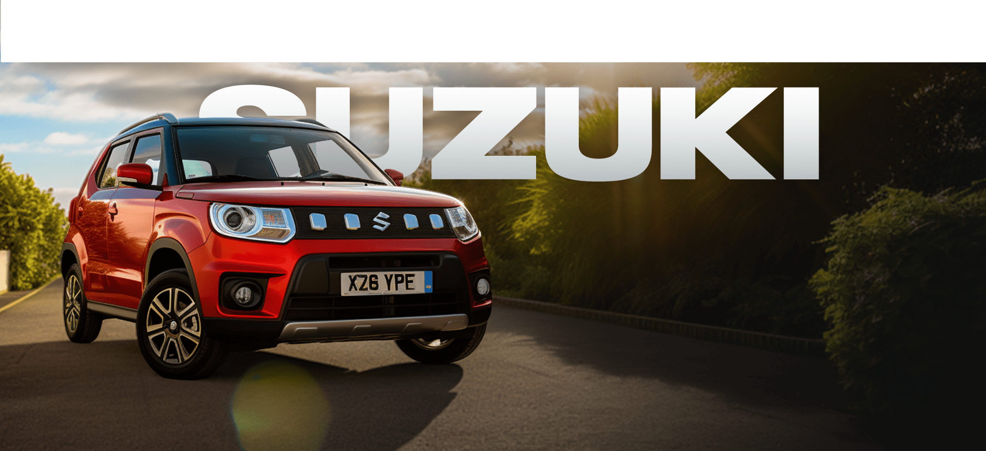 A red Suzuki car is parked on a road, facing slightly left. The background features greenery, while the large, bold text "SUZUKI" is displayed behind the car. The license plate reads "X26 YPE." The scene is bathed in natural daylight.