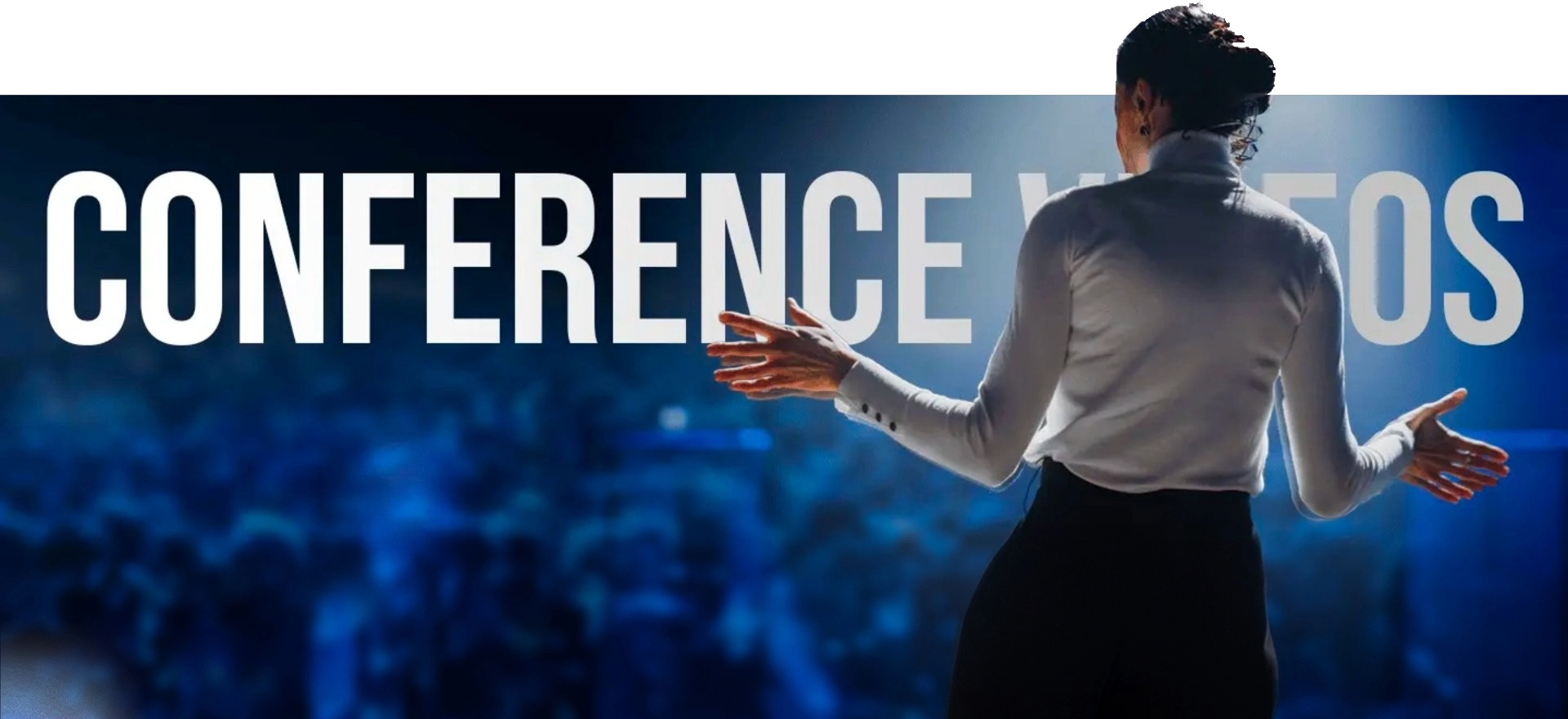 A Person Stands On A Stage, Gesturing With Their Hands, Facing A Large Audience. The Words &Quot;Conference Videos&Quot; Are Displayed Prominently In The Background, Partially Obscured By The Person. The Scene Is Illuminated By Bright Lighting, Creating A Focused Atmosphere Reminiscent Of A Promotional Video Company'S High-Quality Production. A person stands on a stage, gesturing with their hands, facing a large audience. The words "CONFERENCE VIDEOS" are displayed prominently in the background, partially obscured by the person. The scene is illuminated by bright lighting, creating a focused atmosphere reminiscent of a promotional video company's high-quality production.